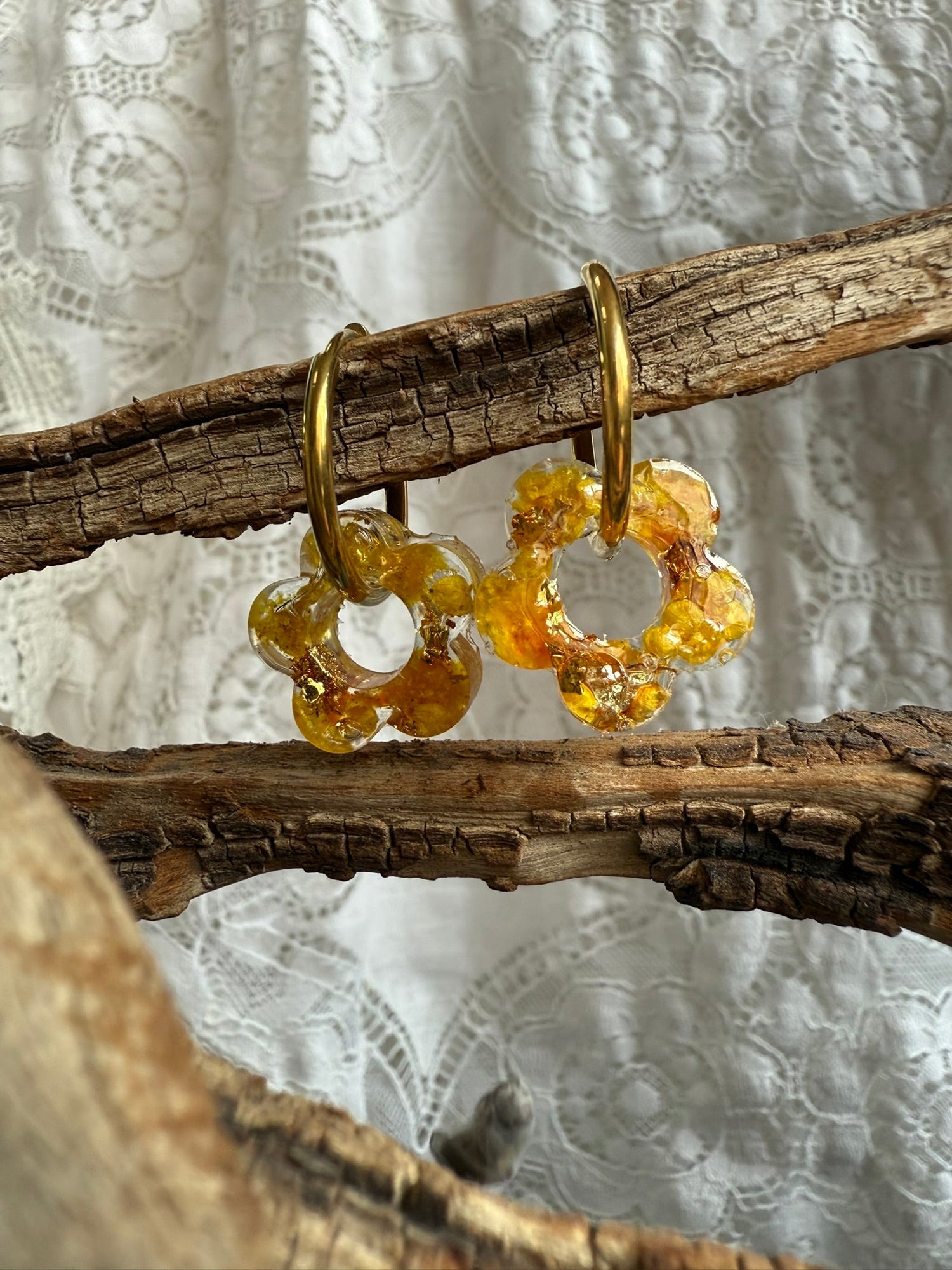 Boucles d’oreilles en forme de fleur avec fleurs séchées jaunes encapsulées dans une résine transparente, sur créole dorée